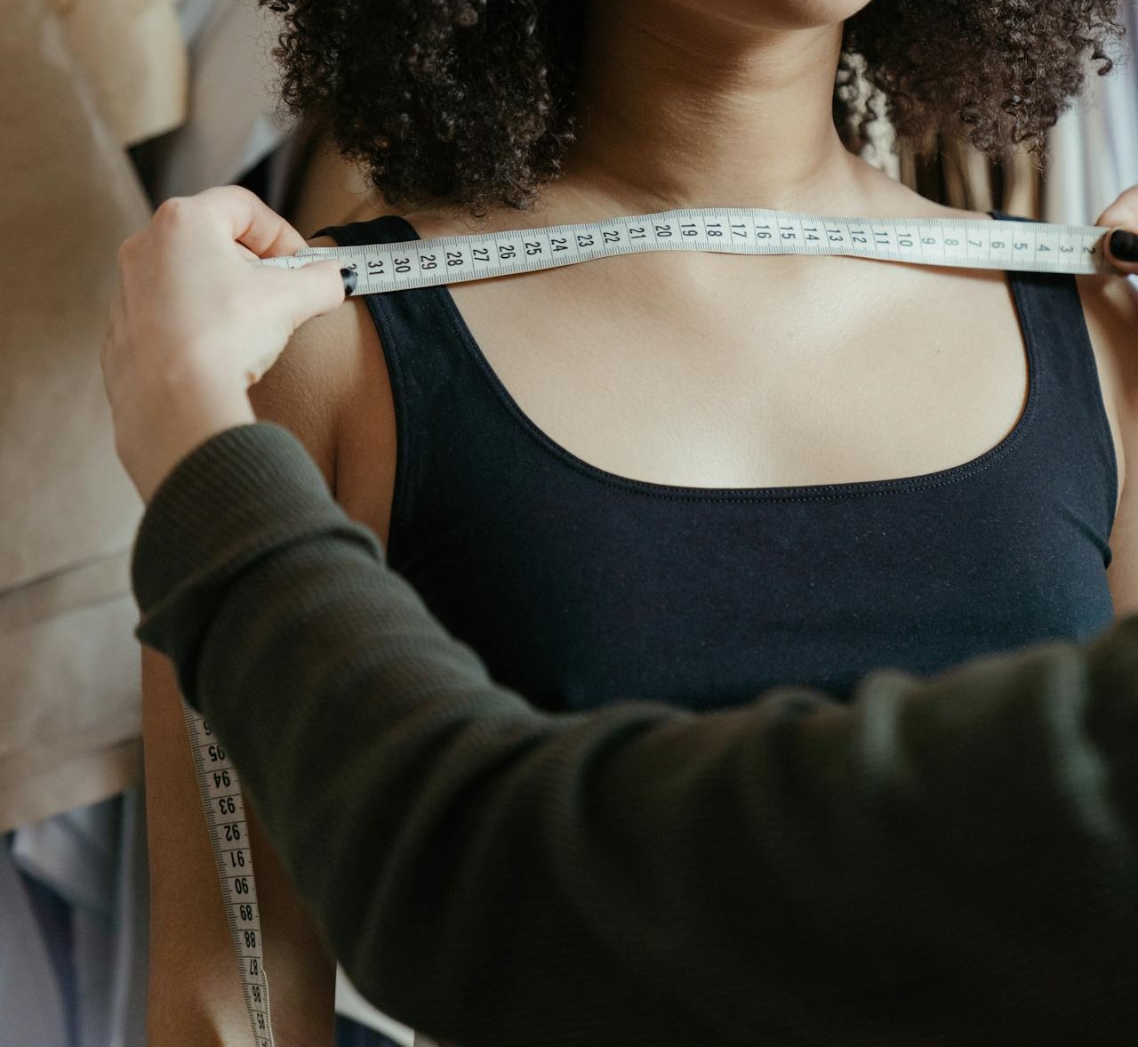 A tailor measures someone's shoulders